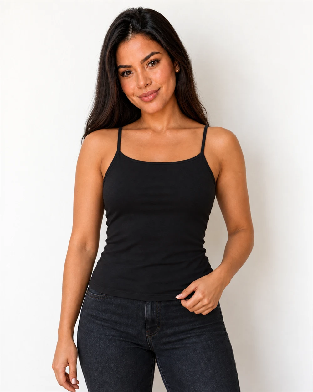 Maya com a regata preta de alça fina e calça jeans, ajeitando a barra na altura do quadril.
